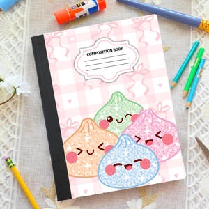 May include: A composition book with a light pink and white checkered pattern featuring four glittery, smiling dumpling characters in orange, green, pink, and blue. The cover includes a white label with the text COMPOSITION BOOK and lines.