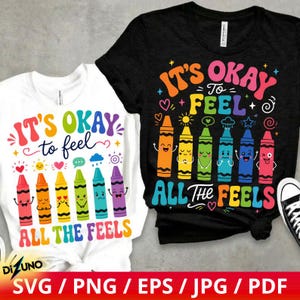 Può includere: Una t-shirt bianca e una t-shirt nera, ciascuna con una grafica colorata di sei pastelli antropomorfi con varie espressioni facciali. Il testo recita "IT'S OKAY TO FEEL ALL THE FEELS", con le parole scritte in lettere dai colori dell'arcobaleno.