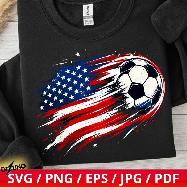 May include: A black crewneck sweatshirt featuring a graphic print of a football integrated with a stylised, brushstroke-effect American flag design in red, white, and blue. The Gildan brand tag is visible at the inner neckline of the garment.