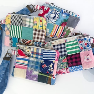 May include: Four patchwork fabric zipper pouches with denim wrist straps. The pouches feature a variety of colorful fabric squares in patterns like plaid, stripes, and floral prints. The wrist straps are a blue checkered pattern.