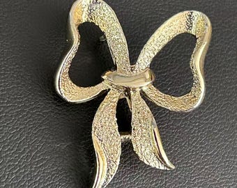 Broche vintage firmado de Gerrys con lazo en tono dorado y cinta texturizada.