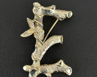 Broszka z inicjałem E w kolorze złotym z bambusową gałązką i sygnaturą Sarah Coventry w kolorze złotym