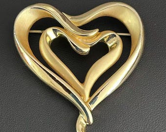 Broche vintage de doble corazón en tono dorado con cinta superpuesta y alfiler abierto.