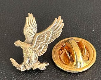 Broszka z motywem amerykańskiego orła w kolorze złotym, przedstawiająca ptaka siedzącego na gałęzi
