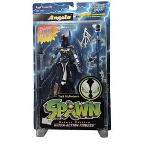May include: A Special Limited Edition Angela action figure from Todd McFarlane's Spawn series. The figure is in a clear plastic package with a blue and black background. The figure is dark blue with gold accents and comes with multiple accessories.