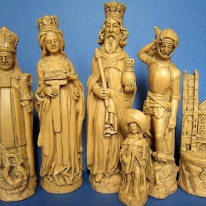 May include: A set of ivory-coloured chess pieces, including a king, queen, bishop, knight, pawn, and a castle. The pieces are intricately detailed, depicting figures with crowns, robes, and armour. The chess set is displayed against a blue background.