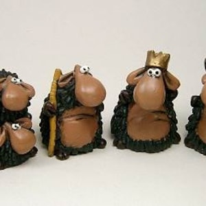 Puede incluir: Colección de figuras de ovejas caprichosas con abrigos lanudos verde oscuro y caras marrones grandes. Algunas ovejas llevan coronas doradas o sostienen un bastón. Una oveja está sobre una estructura de madera.