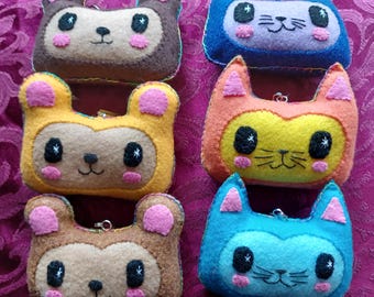 May include: A collection of six handmade felt animal-shaped coin purses. The purses feature bear and cat designs in various colors, including brown, yellow, blue, and orange. Each purse has a zipper and pink accents on the ears and cheeks.
