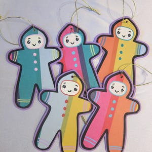 May include: Five colorful paper gingerbread people ornaments with striped bodies and smiling faces. Each ornament has a gold string attached for hanging.