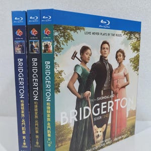 May include: Blu-ray box set of the series "Bridgerton" with three cases visible. The cases are blue with the show's title and images of the cast. The text "Love Never Plays by the Rules" is printed on the largest case.