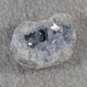 May include: A light blue celestite geode with a crystal cluster inside. The geode is about 2 inches in diameter and has a rough, natural exterior.