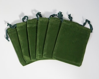 May include: Seven green velvet drawstring pouches with dark green drawstrings. The pouches are arranged in a fan shape.