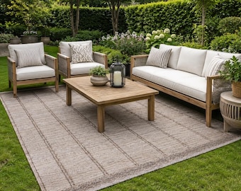 Peut inclure: Un ensemble de mobilier d'extérieur comprenant un canapé en bois et deux fauteuils assortis avec des coussins blancs et des oreillers à motifs. Une table basse rectangulaire en bois est posée sur un grand tapis rayé marron texturé.