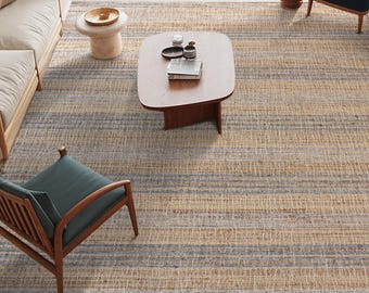 Peut inclure: Un grand tapis de sol à rayures horizontales beiges et bleues. Le tapis est dans un salon, avec une table basse en bois, des chaises et un canapé. La texture du tapis est visible, ajoutant au décor de la pièce.