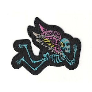 May include: Embroidered patch featuring a skeleton with teal bones, a teal skull, and pink, yellow, and gray wings. The patch is black with a stitched border and depicts the skeleton in a running pose.