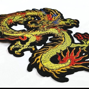Pode incluir: Patch de dragão bordado em amarelo, vermelho e preto. O dragão é retratado em um design estilizado e detalhado com uma borda preta. O patch é provavelmente para roupas ou acessórios.