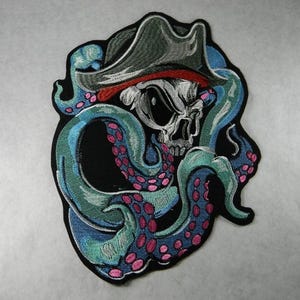 May include: Embroidered patch featuring a skull wearing a pirate hat with a red band, surrounded by teal and pink tentacles. The patch has a black background and is outlined in black.