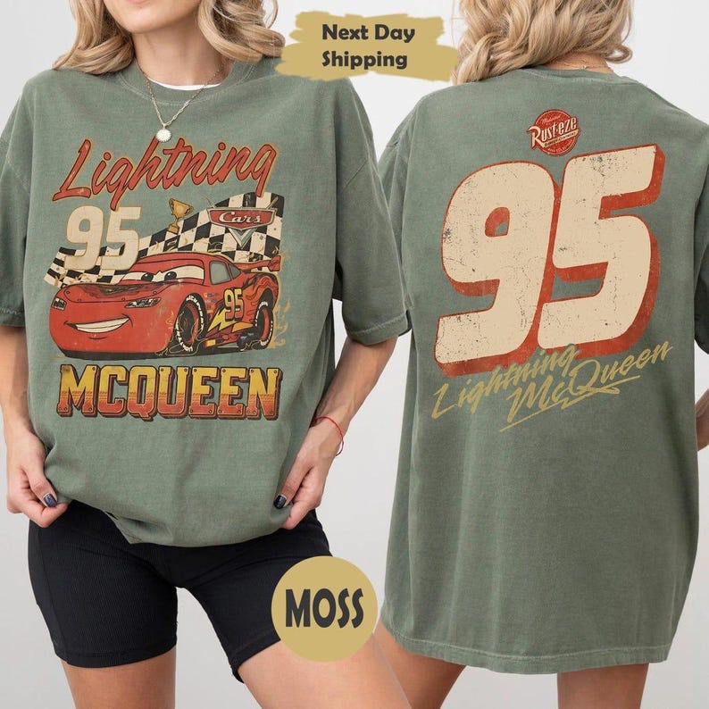 May include: Moss green t-shirt featuring Lightning McQueen from the Cars movie. The front graphic shows McQueen with the number 95 and the text "Lightning McQueen". The back of the shirt has a large "95" and "Lightning McQueen" text.
