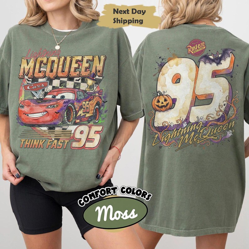 May include: A moss green t-shirt featuring a graphic of Lightning McQueen on the front with the text Lightning McQueen, Cars, and Think Fast 95. The back displays a large 95 with a pumpkin, a bat, and the text Rust-eze and Lightning McQueen.