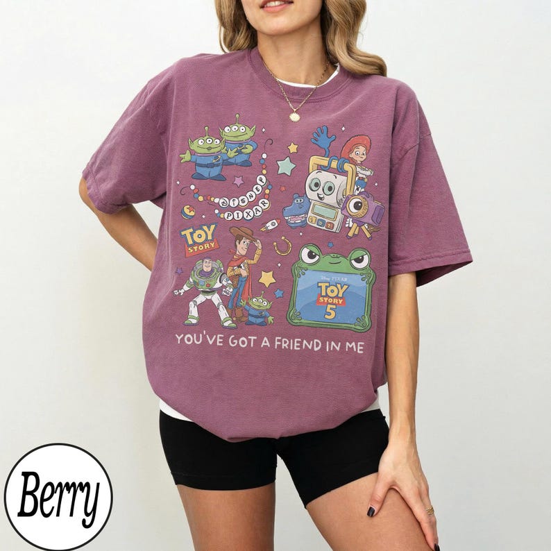 Puede incluir: Una camiseta de manga corta color baya con un estampado gr&aacute;fico de personajes de Toy Story, incluyendo a Woody, Buzz Lightyear y alien&iacute;genas. El dise&ntilde;o incluye el texto "Toy Story", "Toy Story 5" y "You've Got A Friend In Me" con estrellas.