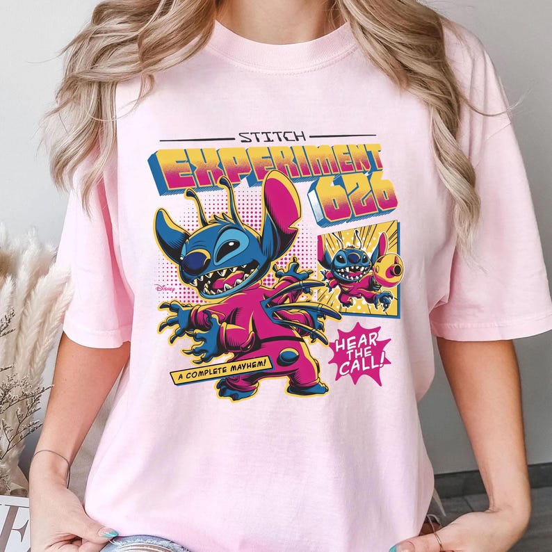 Puede incluir: Camiseta rosa claro con un dise&ntilde;o de Stitch de Lilo & Stitch. El dise&ntilde;o incluye el texto "STITCH EXPERIMENT 626" en una fuente retro, junto con las frases "A COMPLETE MAYHEM!" y "HEAR THE CALL!". El personaje est&aacute; representado en azul y rosa.