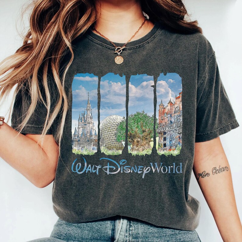 May include: A charcoal gray t-shirt featuring a graphic print of four vertical panels displaying Walt Disney World landmarks, including a castle, a geodesic dome, a large tree, and a tower, with the text Walt Disney World printed below.