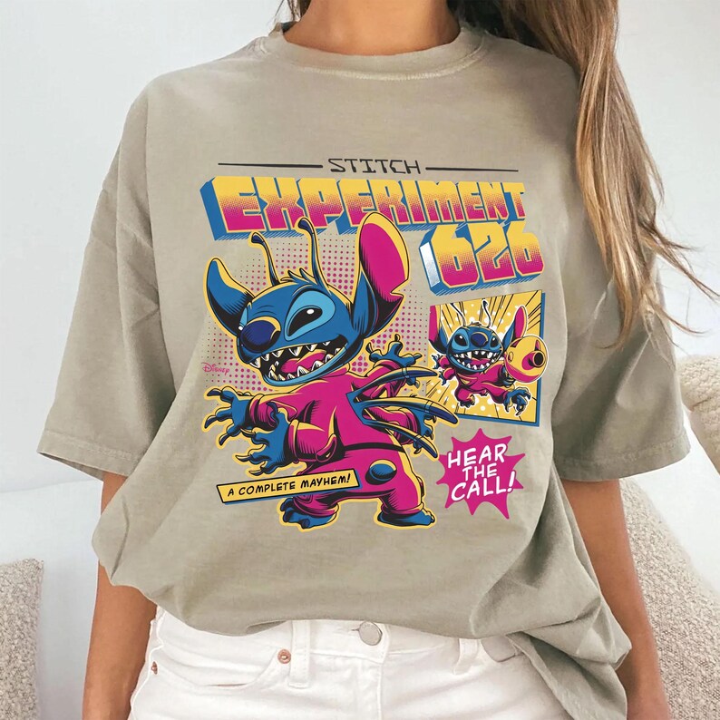 Puede incluir: Camiseta marr&oacute;n claro con un gr&aacute;fico colorido de Stitch de Lilo & Stitch. El dise&ntilde;o incluye el texto "Stitch Experiment 626", "A Complete Mayhem!" y "Hear the Call!" en estilo c&oacute;mic.