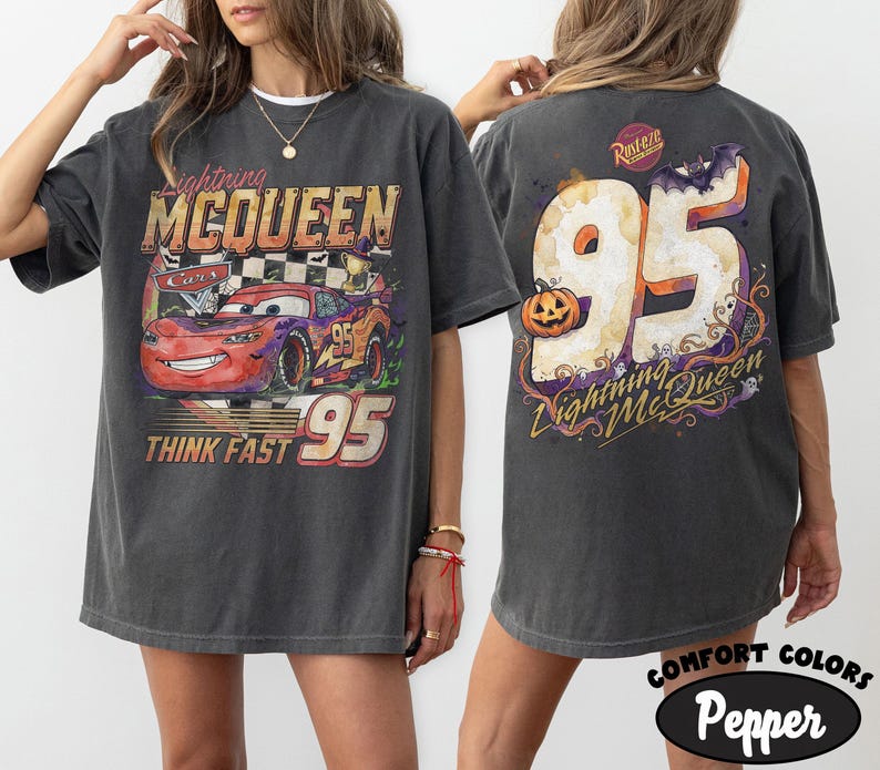 May include: A charcoal gray t-shirt featuring a graphic of Lightning McQueen from Cars on the front with the text Lightning McQueen, Cars, and Think Fast 95. The back displays a large 95 with a pumpkin, a bat, and the text Lightning McQueen.