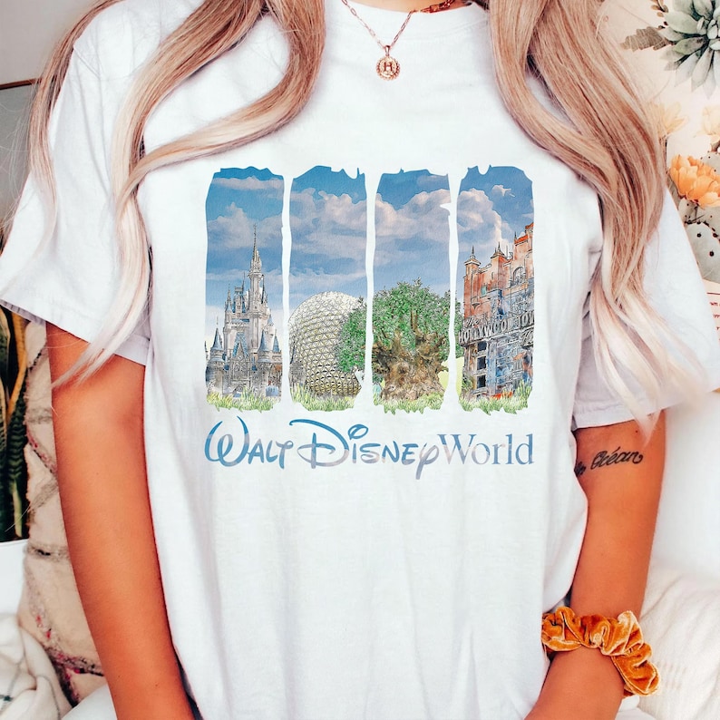 May include: A white t-shirt featuring a graphic print of four vertical panels displaying Walt Disney World landmarks, including Cinderella Castle, Spaceship Earth, the Tree of Life, and the Hollywood Tower Hotel, with the text Walt Disney World below.
