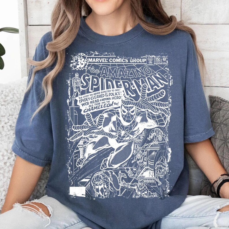 Pu&ograve; includere: Una t-shirt blu con una stampa grafica bianca di una copertina vintage di Marvel Comics The Amazing Spider-Man. Il design include il titolo, i dettagli del numero e un'illustrazione di Spider-Man in una posa dinamica.