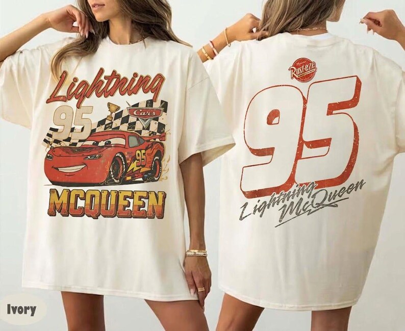 May include: Ivory-colored t-shirt featuring a graphic of Lightning McQueen from the Cars movie. The front displays the car, the number 95, and the name "Lightning McQueen." The back has a large number 95 and the name.