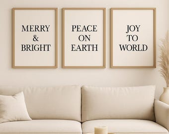 May include: Three framed prints with the phrases "MERRY & BRIGHT", "PEACE ON EARTH", and "JOY TO WORLD" in black text. The frames are a light brown color, and the background of the prints is a cream color. The prints are hanging above a beige sofa.