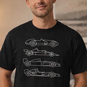 May include: Black t-shirt featuring a white line drawing of four vintage race cars. The cars are depicted in a minimalist style, showcasing their distinct designs. The shirt is a classic crew neck.