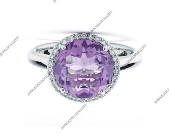 May include: A silver ring featuring a large, round, light purple gemstone encircled by a halo of smaller, clear gemstones. The ring's band is smooth and polished, reflecting the light. The setting highlights the central stone's facets.