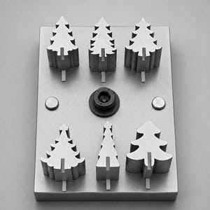 May include: A rectangular metal plate featuring six raised, three-dimensional evergreen tree shapes arranged in two rows. A single black circular bolt is positioned in the centre, flanked by two small, flat, circular metal rivets on the sides.