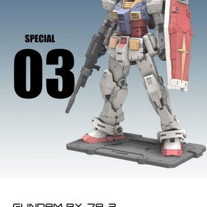 May include: A detailed model of the Gundam RX-78-2, a mecha robot, standing on a gray base. The model is primarily white with red, blue, and yellow accents. It holds a rifle and a red shield. The text "SPECIAL 03" is displayed.
