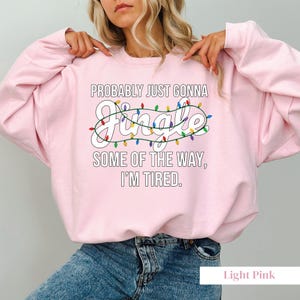 A woman wearing a pink sweatshirt with a humorous text printed on it.