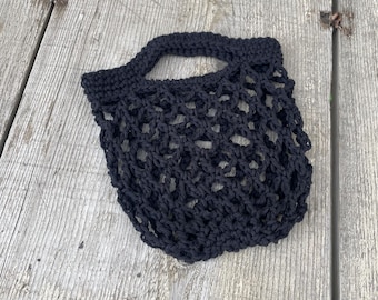 May include: A black crocheted mesh bag with a handle. The bag is made of thick yarn and has a simple, classic design.