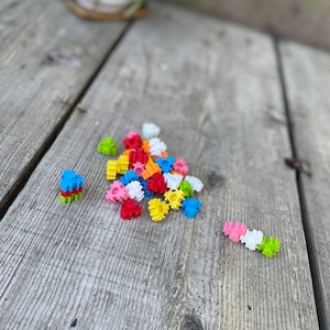 May include: A pile of colorful plastic building blocks in the shape of stars. The blocks are scattered on a wooden surface.