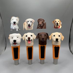 Könnte beinhalten: Vier Bierhahn-Griffe mit Hunde-Motiven, die jeweils eine andere Rasse darstellen: ein weißer Terrier, ein gelber Labrador, ein Schokoladen-Labrador und ein goldener Labrador. Die Griffe haben orangefarbene und schwarze Akzente und silberne Basen.