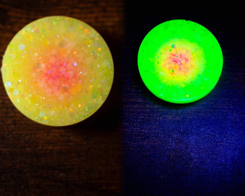 May include: Two round, glittery objects. One is yellow with a pink center, the other glows bright green with a yellow and pink center. The objects are likely decorative or functional items, possibly for crafts or home decor.
