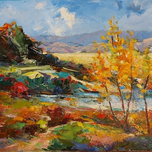 May include: An oil painting of a landscape with a vivid colour palette. The artwork shows a river scene with a mountain range in the background. The foreground features trees with yellow leaves, and the sky is a mix of blue and white.