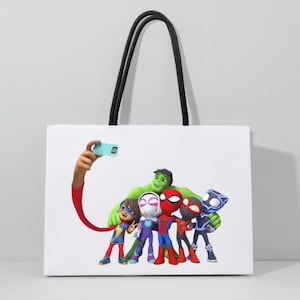 May include: White tote bag with black handles. The bag features a group of cartoon superheroes, including Spider-Man and Hulk, taking a selfie. The superheroes are in colourful costumes. The bag is rectangular and has a simple design.