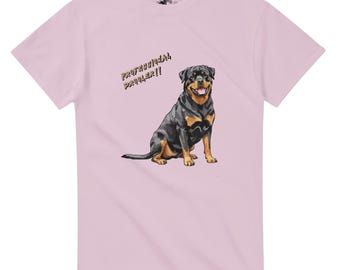 May include: Light pink t-shirt featuring a graphic of a Rottweiler dog with black and brown fur. The text "PROFESSIONAL DROOLER!!" is printed above the dog in a gold color. The shirt has short sleeves and a crew neck.