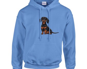 May include: A pale blue hoodie with a graphic of a dachshund dog. The dog is illustrated in black, brown, and tan. The sweatshirt has a front pocket and a drawstring hood. The brand name "Gildan" is visible on the label.