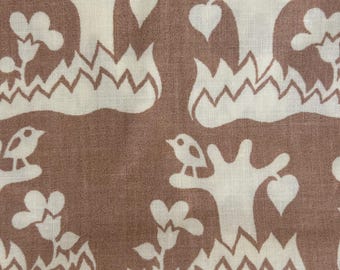 May include: A textile fabric featuring a repeating pattern of off-white stylized trees, small birds perched on branches, and floral shapes set against a solid muted brown background. The design includes jagged, zigzagging lines at the base.