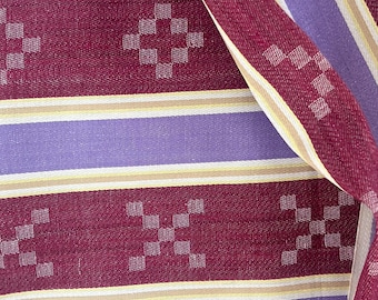 May include: A woven fabric featuring horizontal stripes in deep burgundy, light purple, and thin cream lines. The burgundy sections are decorated with a repeating pattern of small, square-shaped geometric motifs arranged in a cross formation.