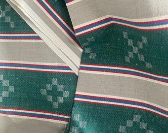 May include: A woven fabric featuring alternating horizontal bands of deep green and light gray. The green sections display a repeating diamond pattern, while the gray sections are accented by thin, parallel stripes in red, white, and blue.