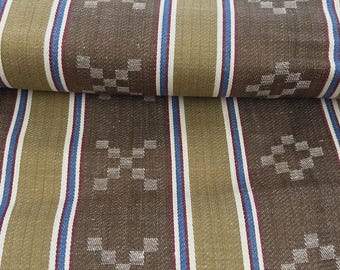 May include: A woven fabric featuring alternating vertical stripes in olive green and dark brown. The pattern includes thin white and blue pinstripes between the wider bands, accented by small, repeating geometric diamond shapes in light gray.