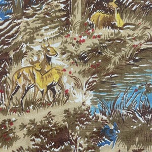 Op de afbeelding: Een geweven stof met een herhalend patroon van herten in een bosrijke omgeving. Het ontwerp bevat bruine, beige en gele herten tussen groen gebladerte, bruine bomen en plekken met blauw water, geaccentueerd door kleine rode bloemendetails.